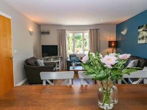 A living room with a sofa, a coffee table, a TV, and a vase with flowers. - Hassop, Matlock - A Charming Retreat (Matlock)