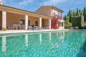 Une piscine avec des chaises longues, un patio couvert et un bâtiment orné de colonnes.