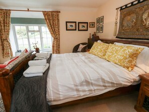 Un dormitorio con cama, cortinas, ventana, decoración en la pared y un cabecero decorativo.