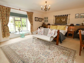 A bedroom with a large bed, a sofa, a chandelier, and a patterned rug.
