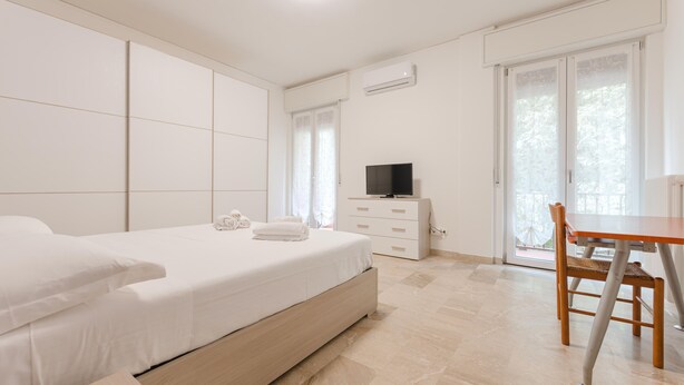Een slaapkamer met een bed, een televisie, een bureau en een stoel.