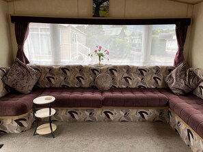 A cozy room with a patterned sofa, a small round table, and a window with curtains.