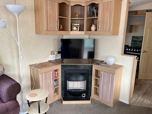 A cozy living room with a fireplace, television, and wooden cabinets.
