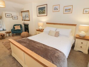 A bedroom with a bed, nightstands, a chair, a mirror, and framed pictures on the wall.