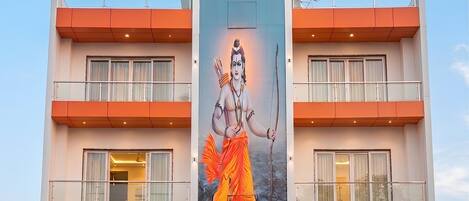 A hotel with a large banner of a deity, balconies, and a covered entrance.