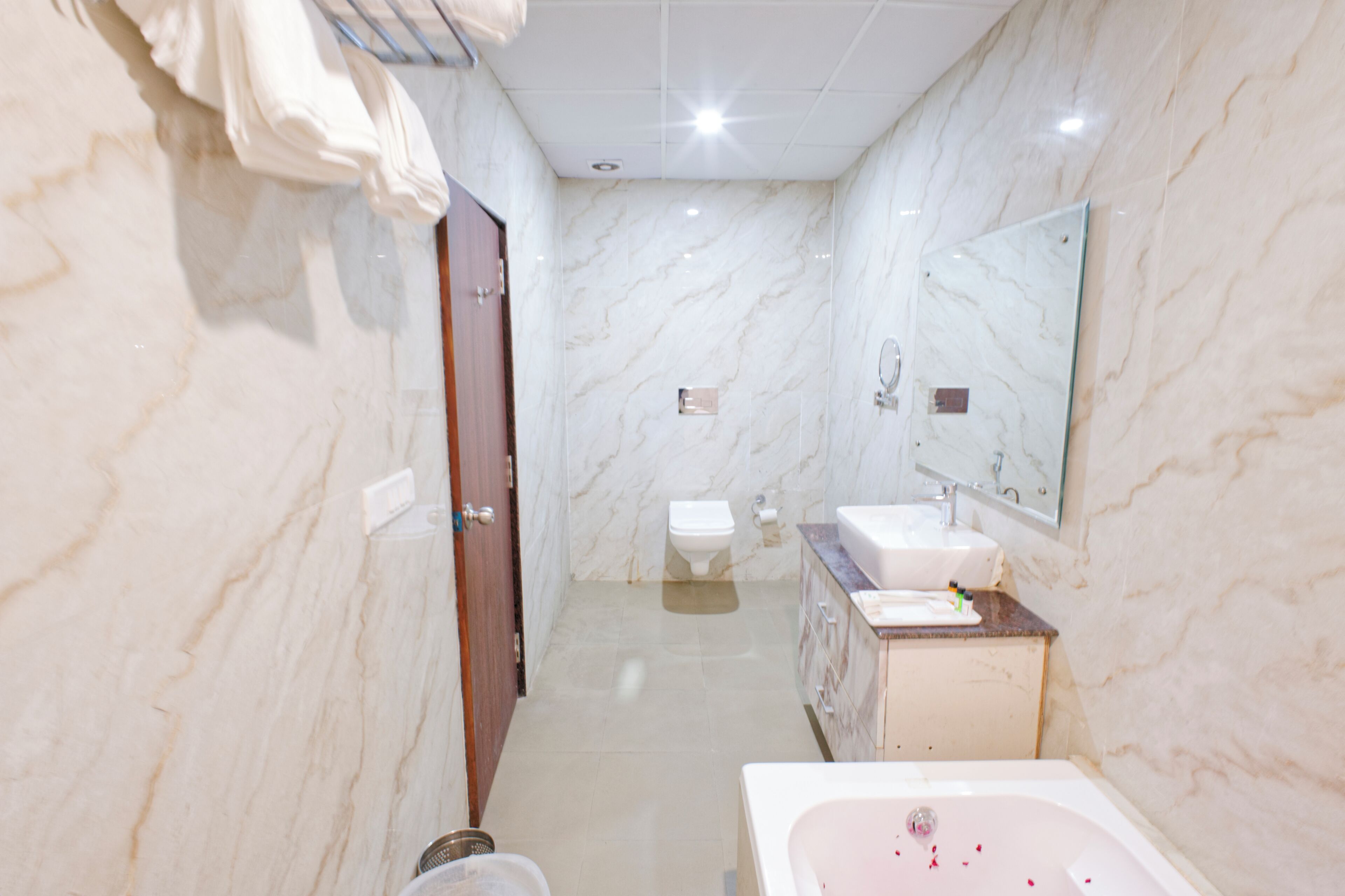 Une salle de bain avec un mur en marbre, des toilettes, un lavabo et une baignoire.