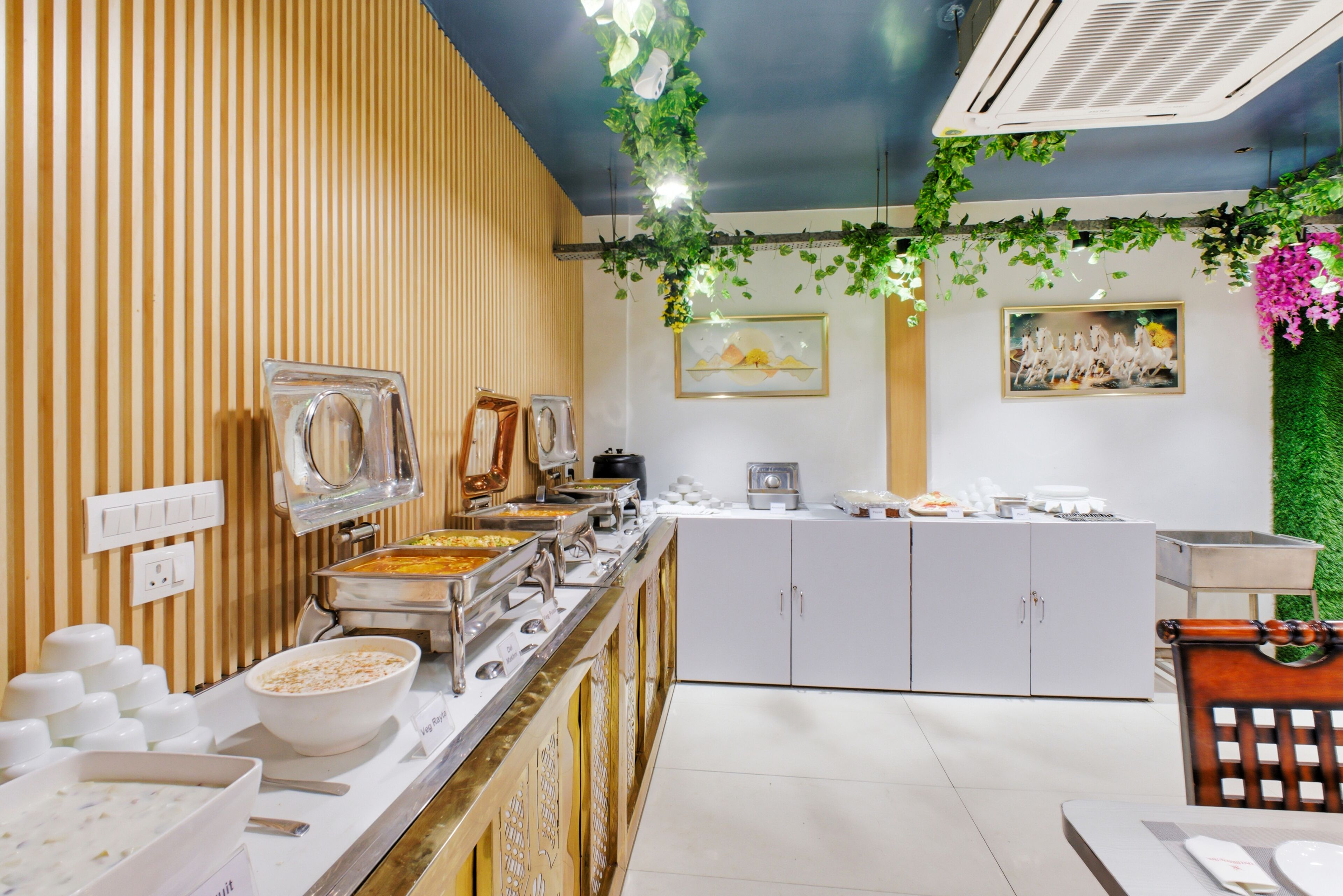 Un espace buffet avec différents postes de service pour les aliments, un comptoir avec des bols et un tableau accroché au mur.