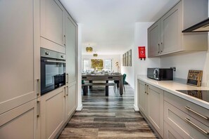 A modern kitchen with built-in appliances, a dining area with a table and chairs, and a view to the dining room. - 2 Riverside Mews, Borrowwash (Derby)