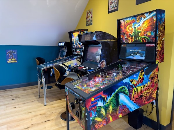 A room with arcade machines, including Star Wars and Godzilla themed games, and a Space Invaders machine.