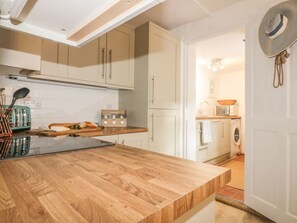 A kitchen with a wooden countertop, white cabinets, and a washing machine in the background. - 14 CLIFF STREET, open-plan,in Mevagissey (St. Austell)