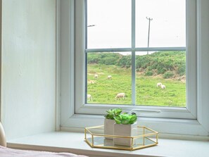 Ein Fenster mit Blick auf ein grünes Feld und Schafe.