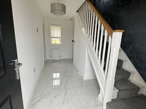 Ein Korridor mit Marmorboden, einer Treppe mit weißen Geländern und einer schwarzen Wand.