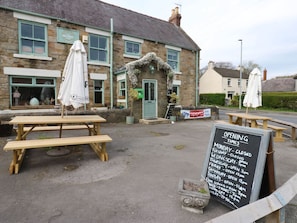 A stone building with a signboard listing opening times. - Charming Premium Cottage 7 (Durham)