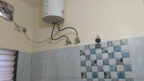 Ein Badezimmer mit Warmwasserbereiter, gefliesten Wänden und einem Fenster mit Jalousien.