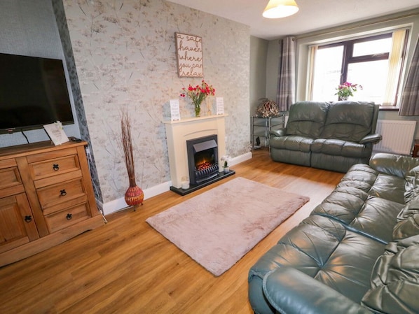 A living room with a fireplace, a sofa, a television, and a decorative wall piece.