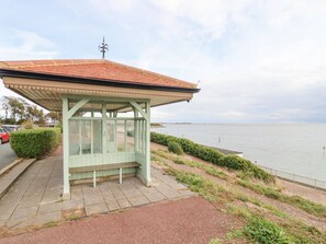 A gazebo with a tiled roof, a bench, and a view of the water.