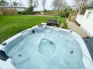 A hot tub in a backyard with a lawn, a wooden fence, and a shed in the background. - Woodlands Close, Padstow (Padstow)