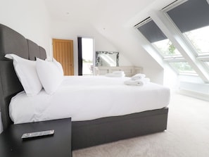 A modern bedroom with a large bed, a bedside table, a remote control, and a skylight. - Woodlands Close, Padstow (Padstow)