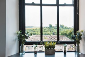 A window with a view of a residential area, a table with potted plants, and a clear sky. - The Residence, Kendal (Kendal)