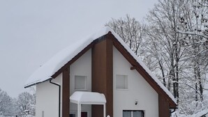 Ett tvåvåningshus med ett snötäckt tak och en inglasad veranda.