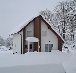 A two-story house with a snow-covered roof and a covered porch. - Holiday House Likarija ⭐️⭐️⭐️⭐️ (Lički Novi)