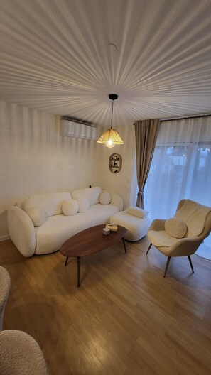 A living room with a sofa, armchair, wooden coffee table, and a hanging lamp. - Holiday House Likarija ⭐️⭐️⭐️⭐️ (Lički Novi)