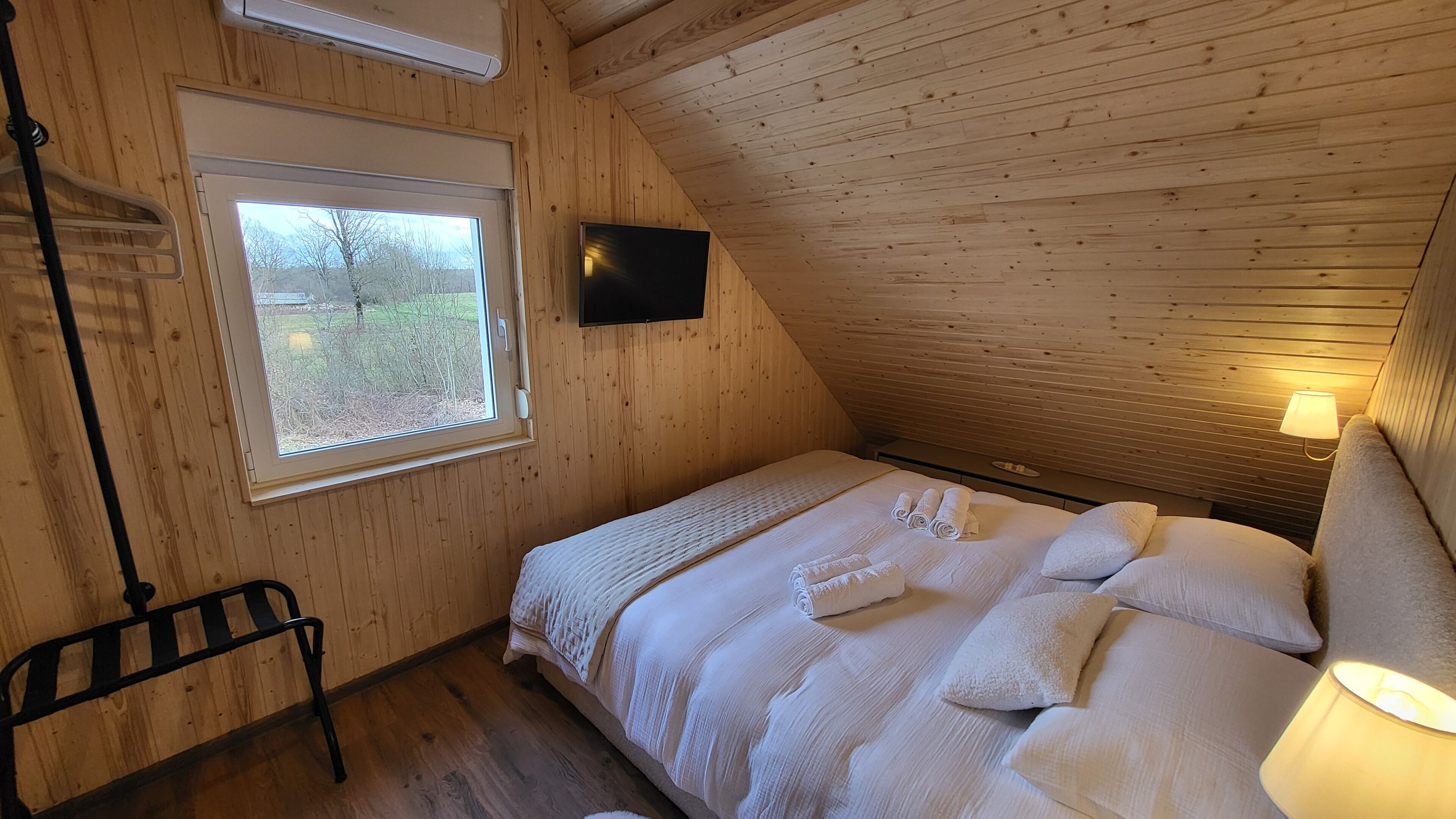 Ett sovrum med en säng, ett fönster, en tv och en lampa.