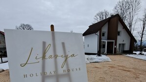En skylt med texten ”Likozja Holiday House” står på ett staffli i ett snötäckt utomhusområde.