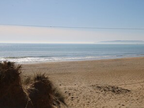 A beach with sand, a clear sky, and a distant landmass. - Charming Sandunes 1 Retreat in Camber (Rye)