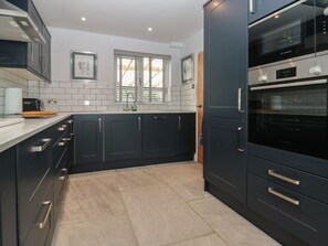 A modern kitchen with dark cabinets, a Bosch oven, and a window with blinds.