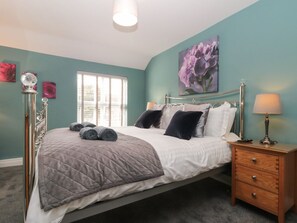 A bedroom with a bed, bedside tables, a window, and a wall-mounted lamp.