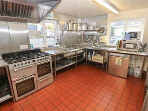 A commercial kitchen with stainless steel appliances, a large stove, ovens, and a microwave.