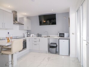 A modern kitchen with white cabinets, a microwave, a sink, and a trash bin. - SJs Annexe rests in Castlerock. (Coleraine)