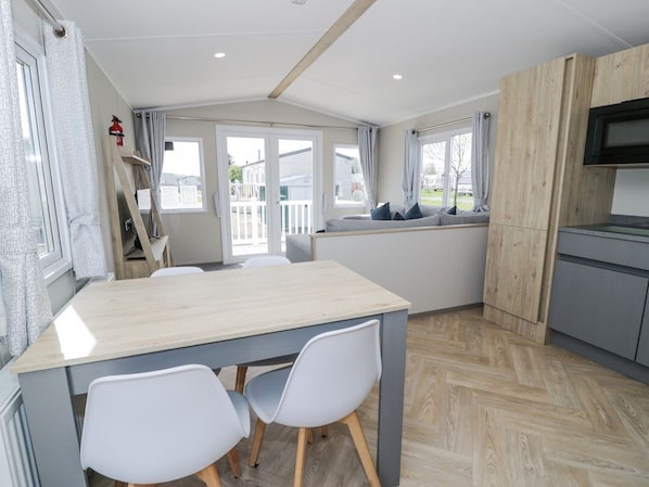 Una cocina moderna con encimera de madera, sillas blancas y vistas al exterior.