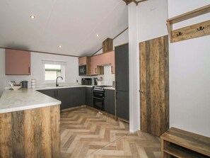 A compact kitchen with a herringbone floor, a built-in oven, and a microwave.