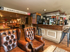 A bar area with leather chairs, a counter with a menu, and a sign that reads 'football it's a game of two halves.'