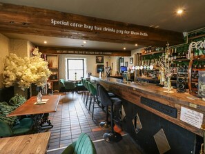 A bar area with a wooden counter, bar stools, and a sign offering a special deal.
