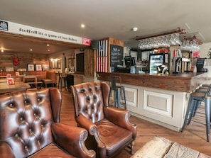 Un espace bar avec des fauteuils en cuir, un comptoir en bois et une pancarte sur laquelle on peut lire : « Le football, c’est un jeu qui se déroule en deux mi-temps. »