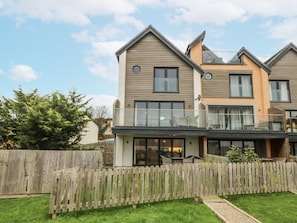 A modern two-story house with a balcony, a wooden fence, and a well-maintained lawn. - Estuary View, Llansanffraid Glan Conwy (Colwyn Bay)