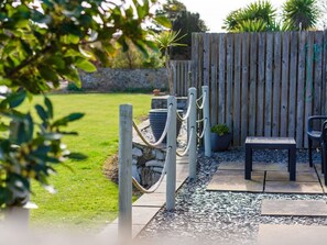 A patio area with a wooden fence, a bench, and a small table. - Charming Ty Woms Retreat in Abersoch (Pwllheli)