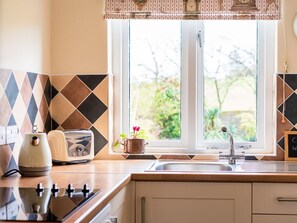 A kitchen with a window, a toaster, a kettle, and a sink. - Charming Ty Woms Retreat in Abersoch (Pwllheli)