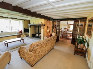 A cozy living room with a sofa, a television, a fireplace, and a dining area visible through an open door. - Dale View, Lealholm, Whitby (Whitby)