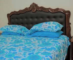 A bed with a dark headboard and blue floral bedding.