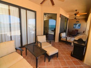 Ein Balkon mit einer Couch, Stühlen, einem Tisch und einem Grill.