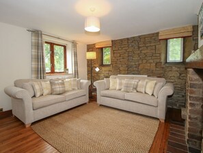 Ein Wohnzimmer mit zwei Sofas, einer Steinwand, einem Kamin und einem Fenster mit Vorhängen.