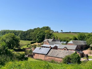 A rural setting with multiple brick buildings, a pond, and a clear blue sky. - The Coach House, Bolney Sussex (Haywards Heath)