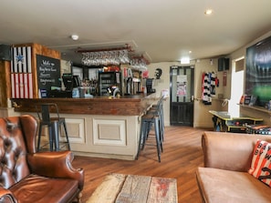 Un espace bar avec des tabourets, un comptoir et un mur orné d’un tableau.