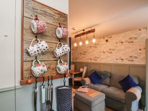 A cozy living area with a wooden wall-mounted mug rack, a sofa, and a patterned wall. - Seaglass, Flamborough (Bridlington)