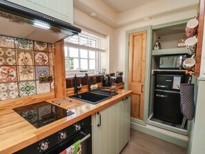 A kitchen with a wooden countertop, a built-in stove, a black refrigerator, and a window with blinds. - Seaglass, Flamborough (Bridlington)