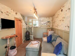 A cozy living room with a sofa, a television, a wooden door, and a staircase leading to another room. - Seaglass, Flamborough (Bridlington)